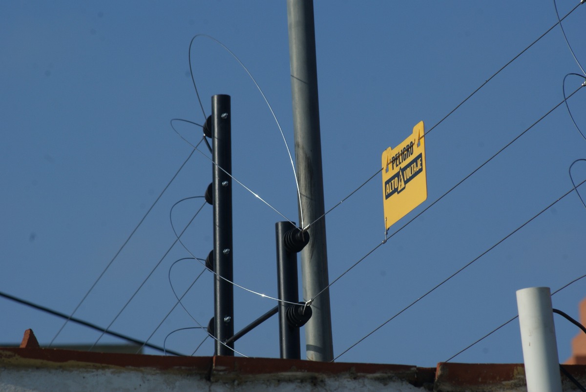 Instalación de un cerco eléctrico perimetral sobre un muro para máxima seguridad.